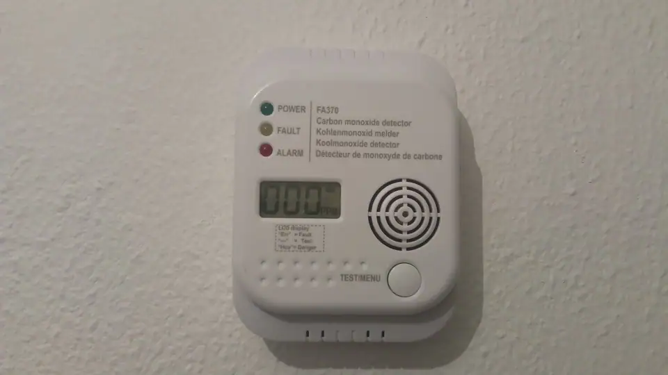 A wall-mounted carbon monoxide detector with a digital display reading zero