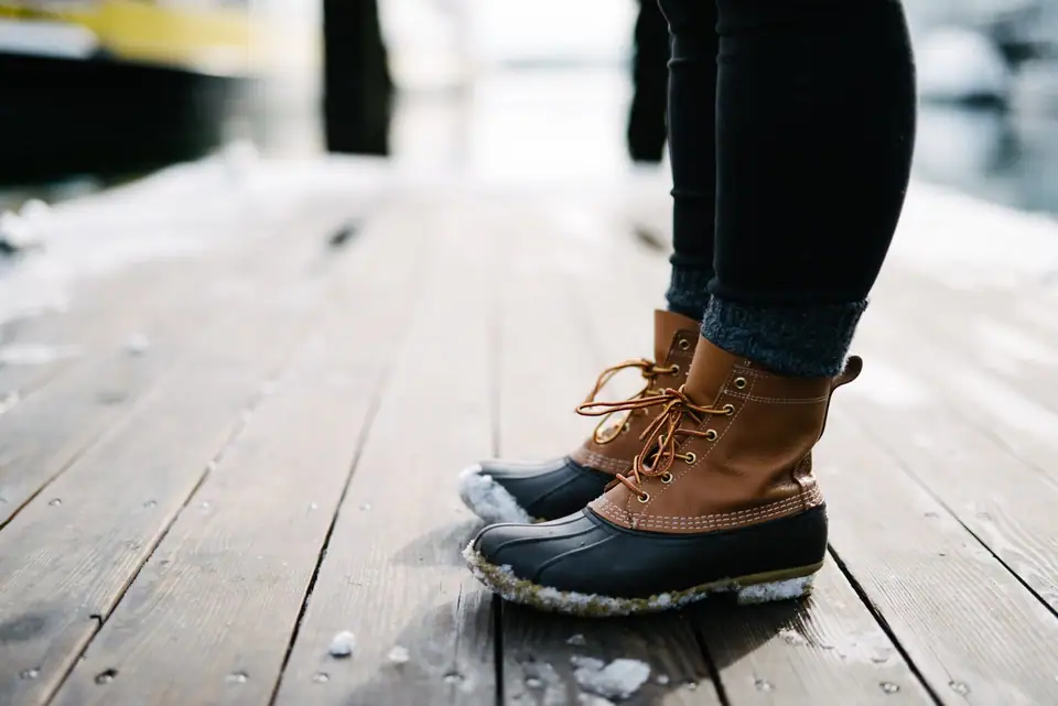 Rubber-bottomed lace-up boots worn with wool socks on a snowy wooden dock