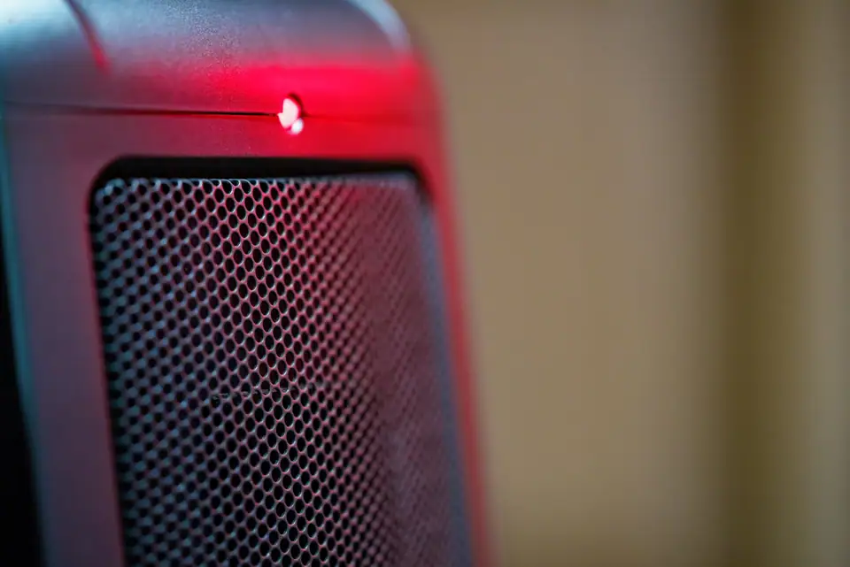 Close-up of an electric ceramic space heater grille with its power light on