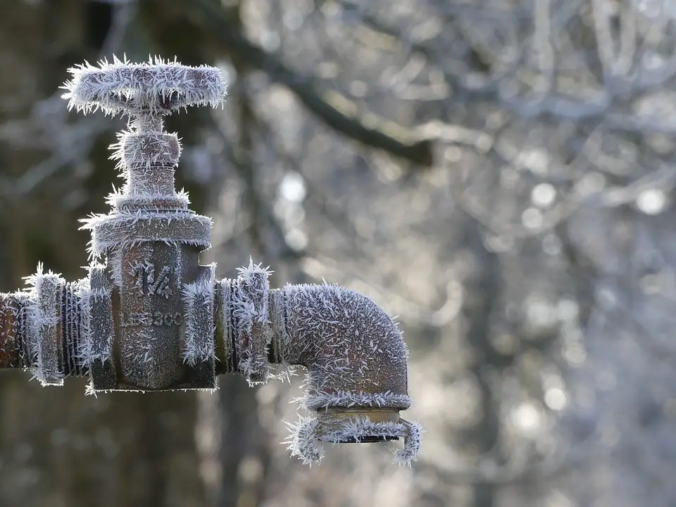 An outdoor faucet and pipe covered in spiky frost crystals