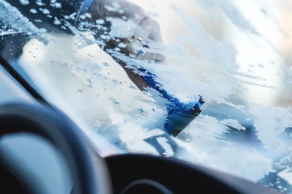 An ice scraper clearing frost from a windshield