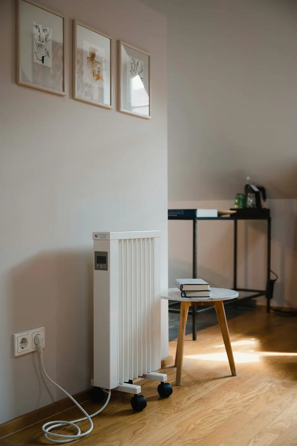 A white oil-filled radiator heater on casters, plugged straight into a wall outlet