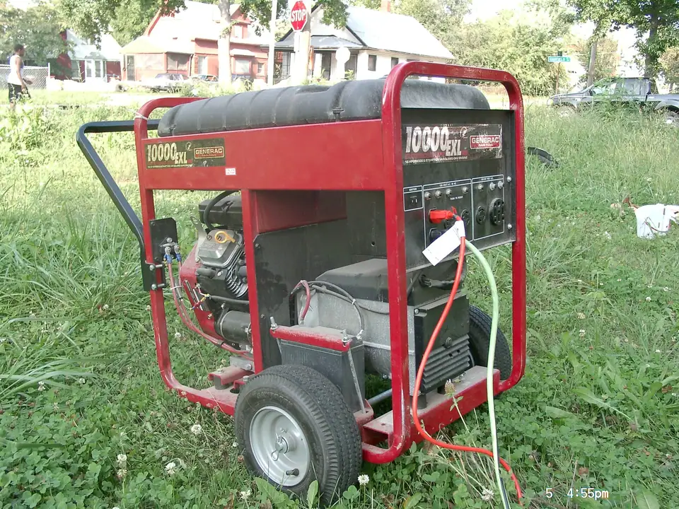 A red-framed portable gasoline generator on wheels standing outdoors on grass