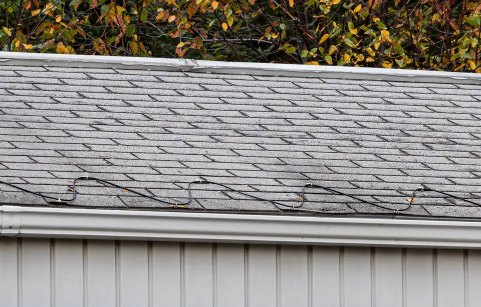 A de-icing heat cable clipped in a zigzag along the shingles just above a gutter